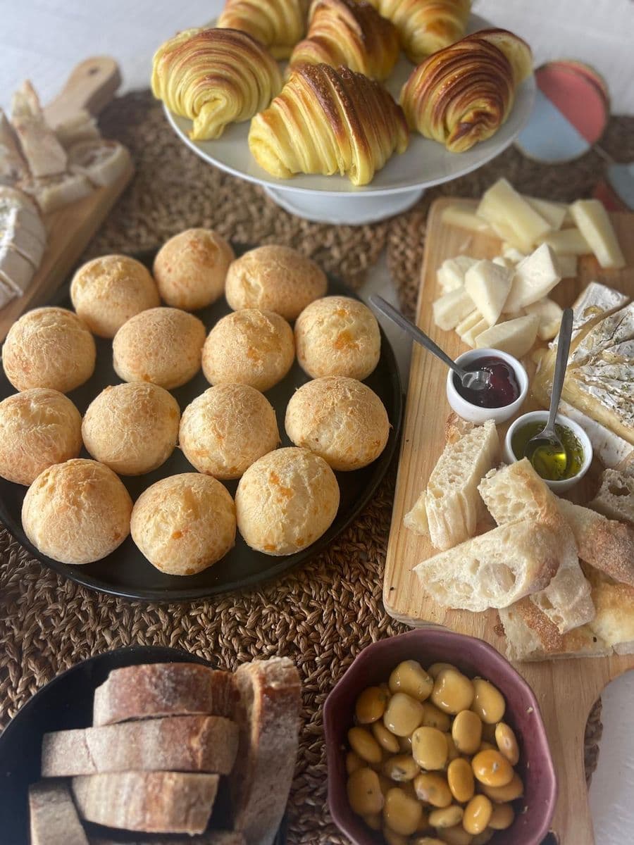 Mesa de brunch do café 55 com rolinhos folhados, pão de queijo, sourdough e tábuas de queijo