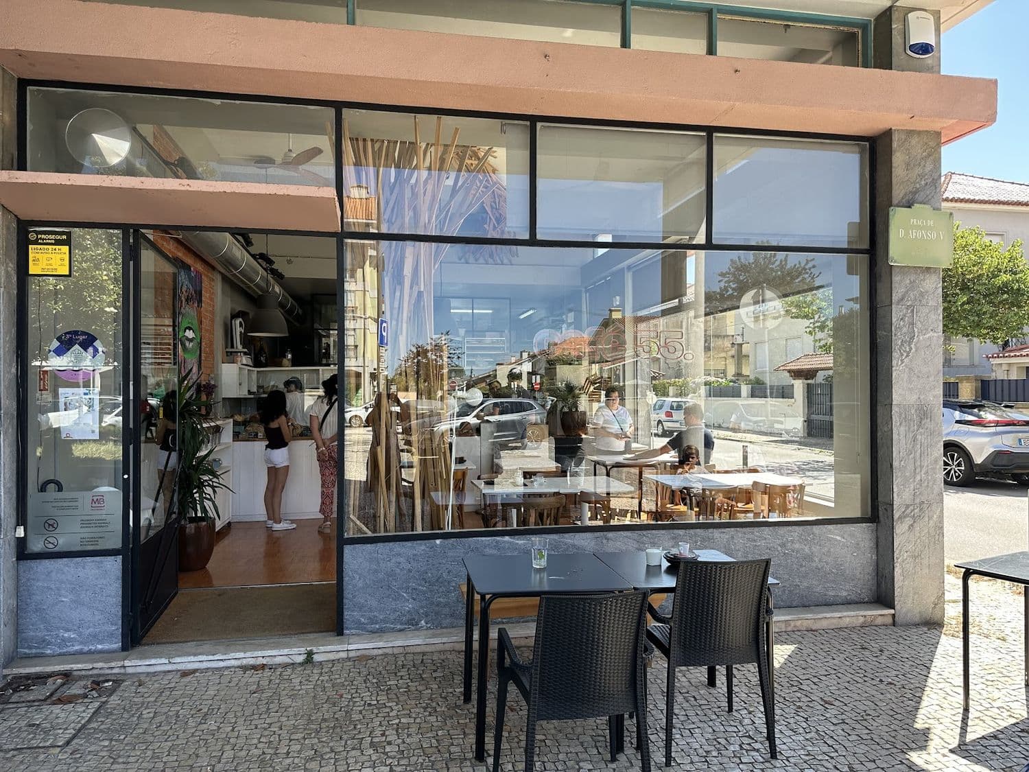 Fachada do café 55 com o letreiro na montra e a placa da Praça de D. Afonso V