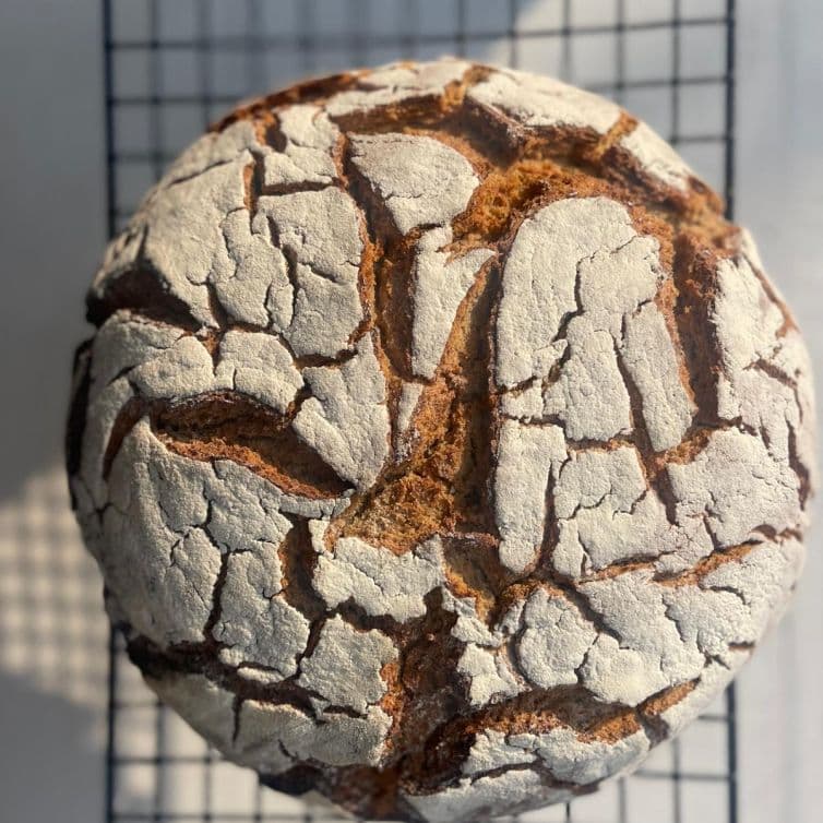 Pão redondo de massa mãe do café 55 com crosta rachada, recém-saído do forno